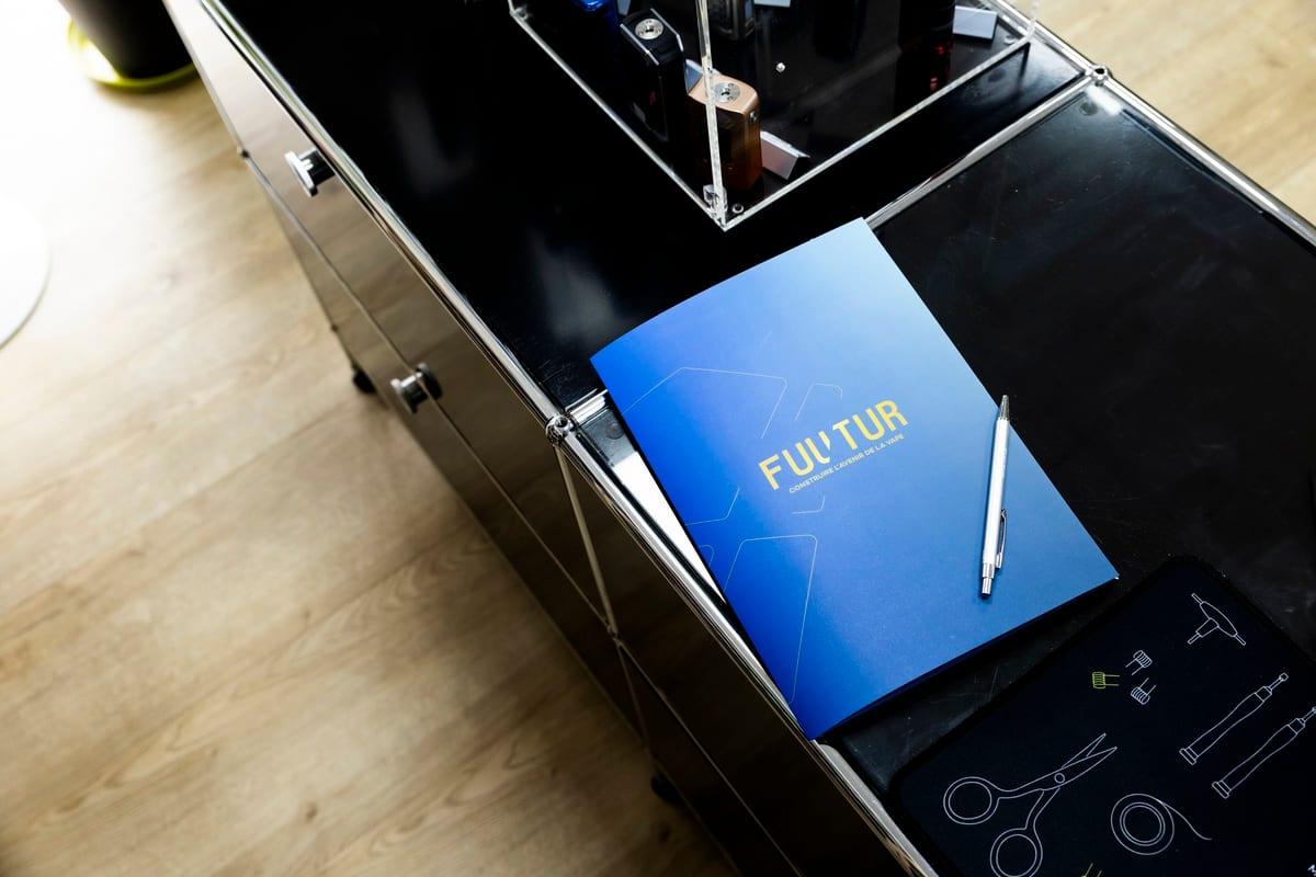 La pochette FUUTUR et un stylo posés sur le comptoir d’une boutique, à côté d’une vitrine de box